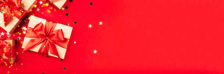 Gift boxes with bows on a red background with confetti. Holiday concept.の写真素材