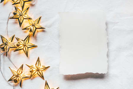 Greeting card for Christmas or New year of golden garlands in the shape of stars with a paper...