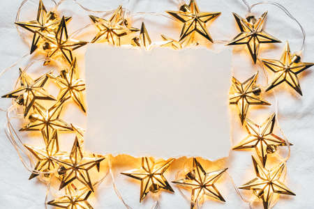 Greeting card for Christmas or New year of golden garlands in the shape of stars with a paper...