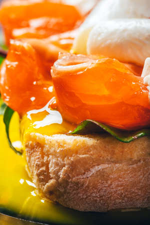 Sandwich with salmon, cheese, herbs and poached egg on black background. Close up.の写真素材