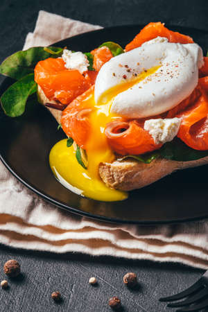 Sandwich with salmon, cheese, herbs and poached egg on black background.の写真素材