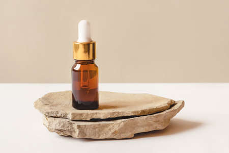 One brown bottle of cosmetics on a natural beige background. Stone podium. Front view.の写真素材