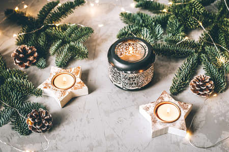 Christmas composition of candlesticks, fir branches and garland on gray background.の写真素材