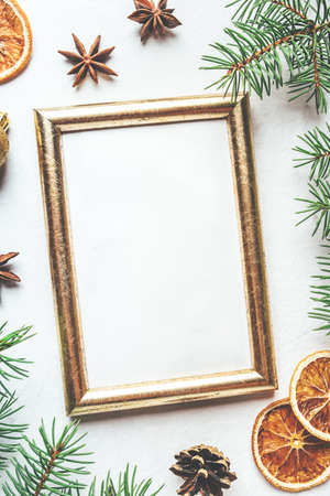 Greeting card for Christmas or New Yaer made of fir branche, spices and dried oranges and a cone with golden frame. Flat lay.の写真素材