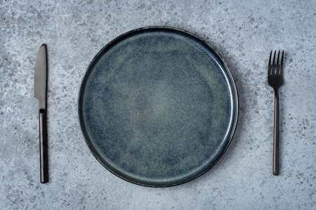 An empty plate and cutlery on a gray table. Top view.の写真素材
