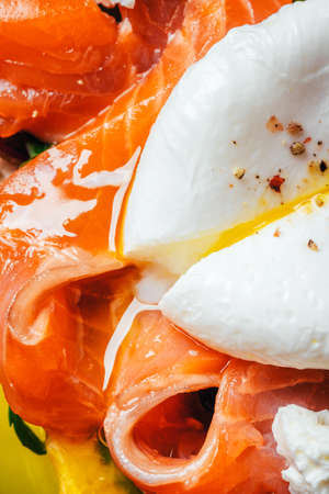 Sandwich with salmon, cheese, herbs and poached egg on black background. Close up.の写真素材