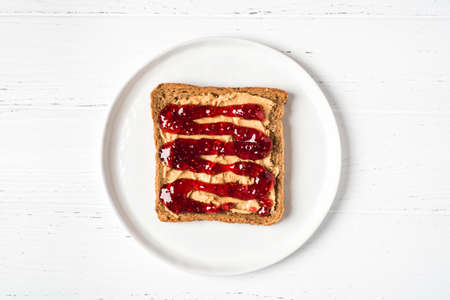 Homemade peanut butter sandwich with raspberry jam on wooden background.の写真素材