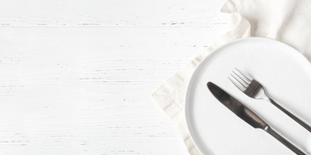 An empty plate and cutlery on a white wooden table. Top view.の写真素材