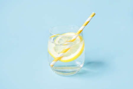 Glass of water with lemon on a blue background. Summer refreshing drink.の写真素材