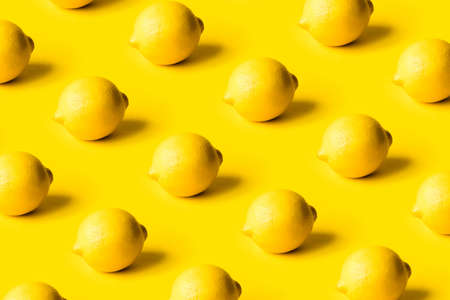 Pattern of ripe lemons on a yellow background. Summer concept.の写真素材