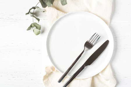 An empty plate and cutlery on a white wooden table. Top view.の写真素材