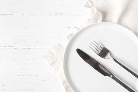 An empty plate and cutlery on a white wooden table. Top view.の写真素材