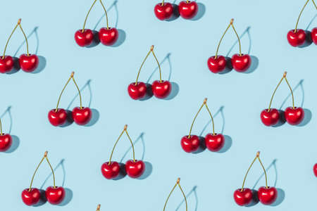 Bright pattern of ripe cherries on a blue background. Flat lay, top view.の写真素材