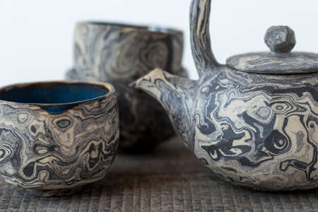 Handmade ceramics in the style of wabi sabi. Clay teapot and cup with an abstract pattern.の写真素材