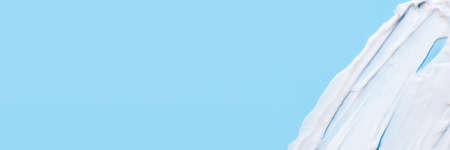 The texture of the skin or hair care product. White smears of cream, mask or balm on a blue...