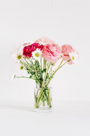 A bouquet of fresh spring flowers in a glass vase on a white table.の写真素材