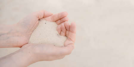 Womens hands hold white beach sand.の写真素材