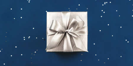 Silver gift box with bow on blue background.の写真素材