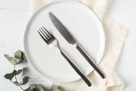 An empty plate and cutlery on a white table.の写真素材