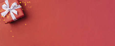 Gift boxe with white bow on a red backdrop.