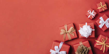 Gift boxes with white and brown bows on a red backdrop.の写真素材