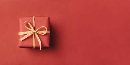 Gift box with brown bow on a red backdrop.の写真素材