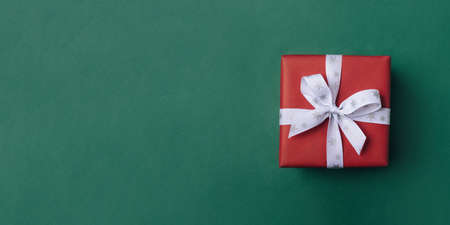 Gift box with white bow on a green backdrop.の写真素材