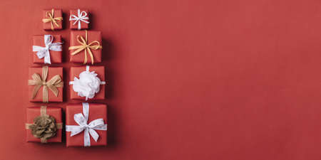 Gift boxes with white and brown bows on a red backdrop.の写真素材
