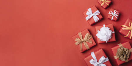 Gift boxes with white and brown bows on a red backdrop.の写真素材