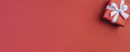 Gift box with white bow on a red backdrop.の写真素材