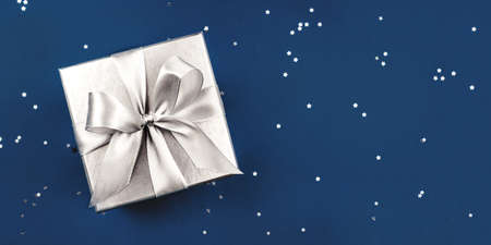 Silver gift box with bow on blue background.の写真素材