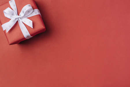Gift boxe with white bow on a red backdrop.の写真素材