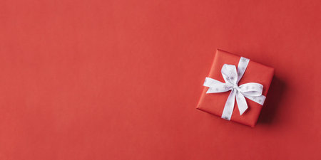 Gift boxe with white bow on a red backdrop.の写真素材