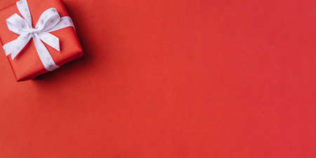 Gift boxe with white bow on a red backdrop.の写真素材