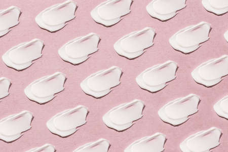 Smear of cream on a pink background.