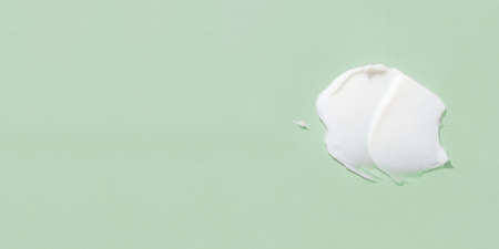 Smear of cream on a green background.の写真素材