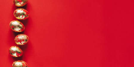 Golden colored and decorated with sparkles Easter eggs on red background.の写真素材