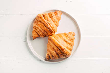 Plate with two fresh croissants on white table.の写真素材