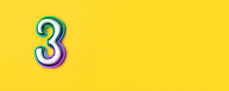 3 years celebration. Banner with birthday greetings. Multi colored metal number three on a yellow background. Copy space, top view.の写真素材