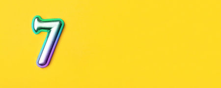 7 years celebration. Banner with birthday greetings. Multi colored metal number seven on a yellow...