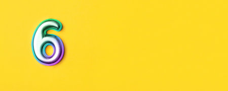 6 years celebration. Banner with birthday greetings. Multi colored metal number six on a yellow background. Copy space, top view.の写真素材
