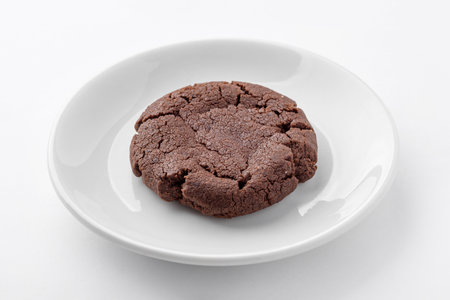 One freshly baked chocolate cookie on a white plate on the table. Homemade bakery for breakfast.の写真素材