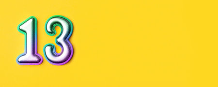 13 years celebration. Banner with birthday greetings. Multi colored metal number thirteen on a yellow background. Copy space, top view.の写真素材