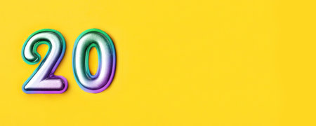 20 years celebration. Banner with birthday greetings. Multi colored metal number twenty on a yellow background. Copy space, top view.の写真素材