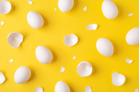 White Easter eggs and shells on a bright yellow background.の写真素材