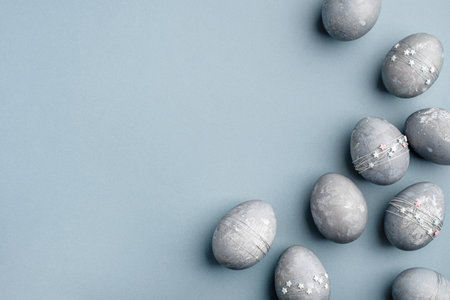 Gray-blue Easter eggs with stars on a blue table.の写真素材