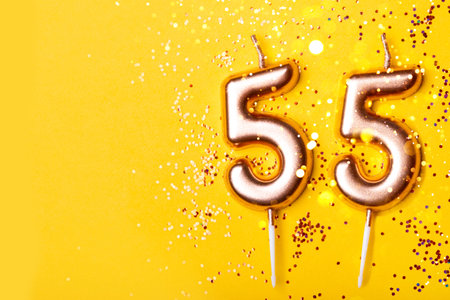 55 years celebration. greeting banner. Gold candles in the form of number forty on yellow background with confetti.の写真素材