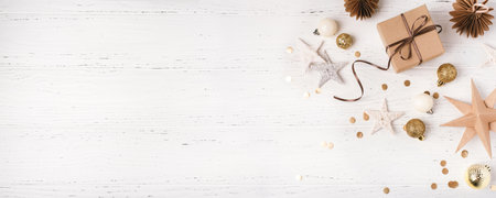 Festive Christmas background with gift box and Christmas decorations on white wooden table. Top...