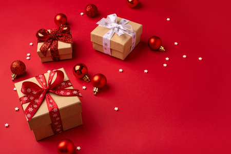 Christmas gift boxes with red balls and white confetti on red background.の写真素材