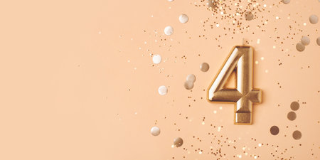 Gold candle in the form of number four on peach background with confetti.